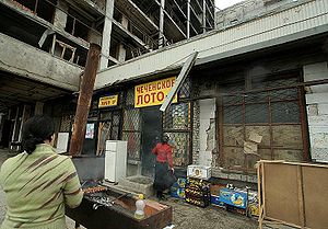 Sidewalk cafe on a summer day.  The sign reads: “Sandnigger lotto”.